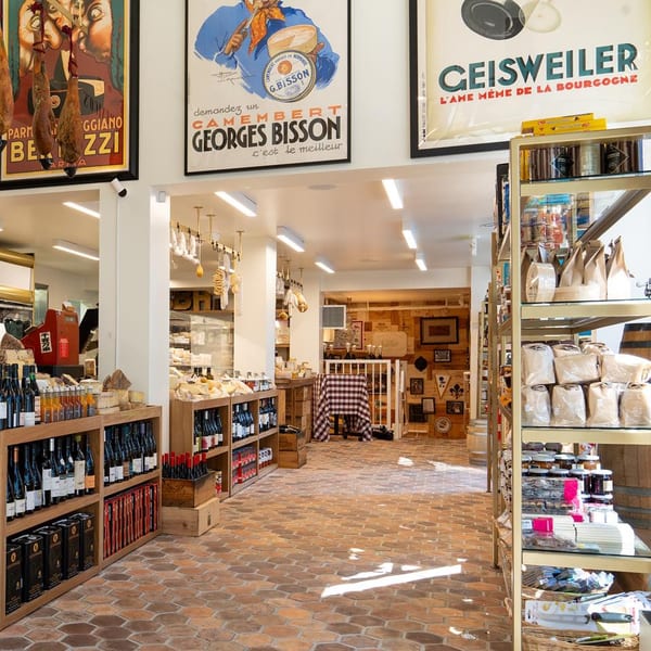 Interior of The Cheese Store of Beverly Hills, featuring wine, cheeses, deli meats, and vintage posters.
